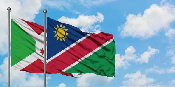 Bandera de Burundi y Namibia ondeando en el viento contra el cielo azul nublado blanco juntos. Concepto diplomático, relaciones internacionales . — Foto de Stock