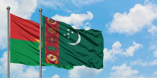 Bandera de Burkina Faso y Turkmenistán ondeando en el viento contra el cielo azul nublado blanco juntos. Concepto diplomático, relaciones internacionales . — Foto de Stock