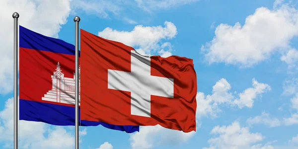 Drapeau du Cambodge et de la Suisse agitant dans le vent contre le ciel bleu nuageux blanc ensemble. Concept de diplomatie, relations internationales . — Photo