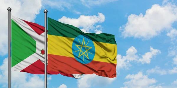 Bandera de Burundi y Etiopía ondeando en el viento contra el cielo azul nublado blanco juntos. Concepto diplomático, relaciones internacionales . — Foto de Stock