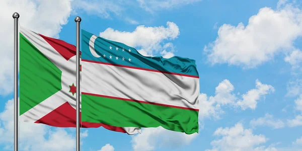 Burundi e Uzbekistan sventolano insieme la bandiera contro il bianco cielo azzurro nuvoloso. Concetto di diplomazia, relazioni internazionali . — Foto Stock