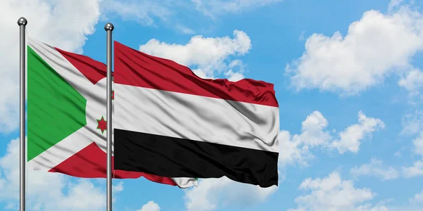 Bandera de Burundi y Yemen ondeando en el viento contra el cielo azul nublado blanco juntos. Concepto diplomático, relaciones internacionales . — Foto de Stock