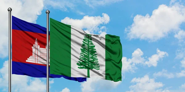 Camboja e Norfolk Island bandeira acenando no vento contra o céu azul nublado branco juntos. Conceito de diplomacia, relações internacionais . — Fotografia de Stock