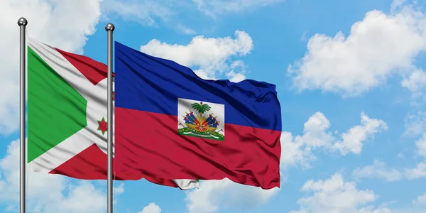 Bandera de Burundi y Haití ondeando en el viento contra el cielo azul nublado blanco juntos. Concepto diplomático, relaciones internacionales . — Foto de Stock