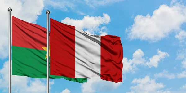 Bandera de Burkina Faso y Perú ondeando en el viento contra el cielo azul nublado blanco juntos. Concepto diplomático, relaciones internacionales . — Foto de Stock