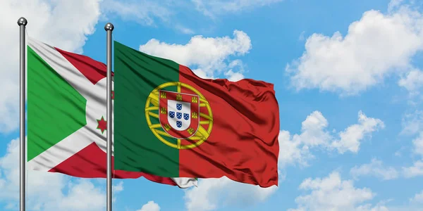 Burundi e bandeira de Portugal agitando no vento contra o céu azul nublado branco juntos. Conceito de diplomacia, relações internacionais . — Fotografia de Stock