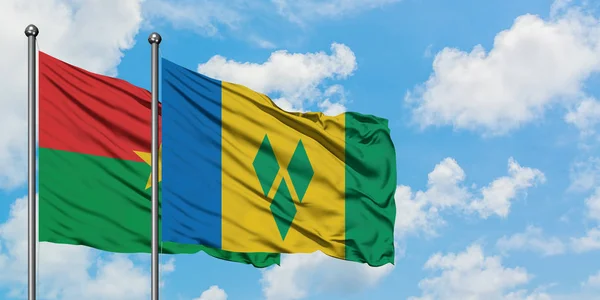 Le Burkina Faso et Saint-Vincent-et-les Grenadines battent ensemble dans le vent contre un ciel bleu nuageux blanc. Concept de diplomatie, relations internationales . — Photo