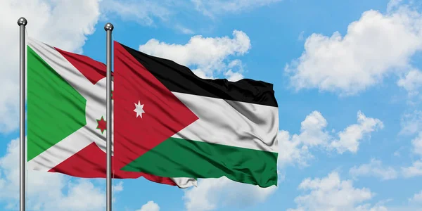 Bandera de Burundi y Jordania ondeando en el viento contra el cielo azul nublado blanco juntos. Concepto diplomático, relaciones internacionales . — Foto de Stock