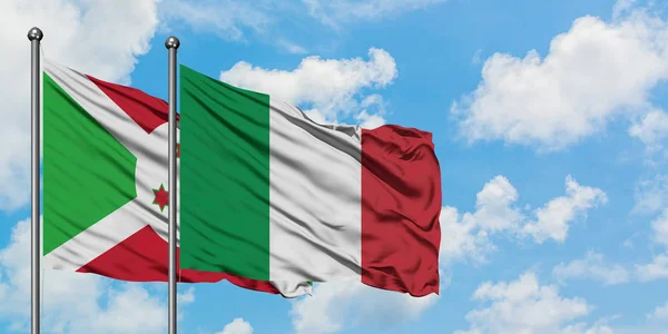 Bandera de Burundi e Italia ondeando en el viento contra el cielo azul nublado blanco juntos. Concepto diplomático, relaciones internacionales . — Foto de Stock