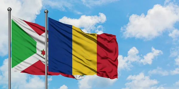 Bandera de Burundi y Rumania ondeando en el viento contra el cielo azul nublado blanco juntos. Concepto diplomático, relaciones internacionales . — Foto de Stock