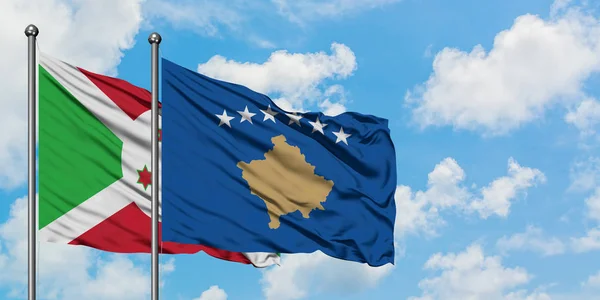 Bandera de Burundi y Kosovo ondeando en el viento contra el cielo azul nublado blanco juntos. Concepto diplomático, relaciones internacionales . — Foto de Stock