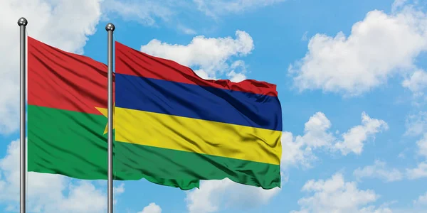 Bandera de Burkina Faso y Mauricio ondeando en el viento contra el cielo azul nublado blanco juntos. Concepto diplomático, relaciones internacionales . — Foto de Stock