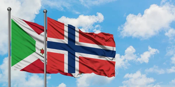 Bandera de Burundi y Noruega ondeando en el viento contra el cielo azul nublado blanco juntos. Concepto diplomático, relaciones internacionales . — Foto de Stock