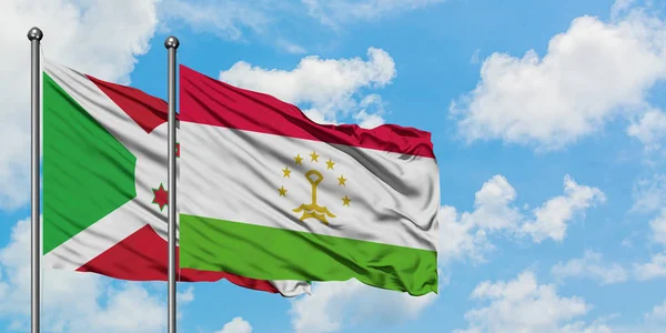 Bandera de Burundi y Tayikistán ondeando en el viento contra el cielo azul nublado blanco juntos. Concepto diplomático, relaciones internacionales . — Foto de Stock