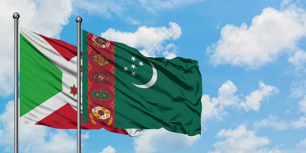 Bandera de Burundi y Turkmenistán ondeando en el viento contra el cielo azul nublado blanco juntos. Concepto diplomático, relaciones internacionales . — Foto de Stock