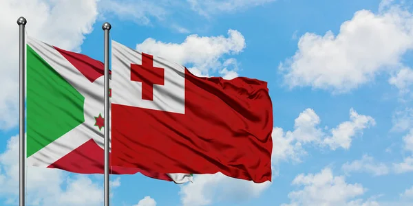 Bandera de Burundi y Tonga ondeando en el viento contra el cielo azul nublado blanco juntos. Concepto diplomático, relaciones internacionales . — Foto de Stock