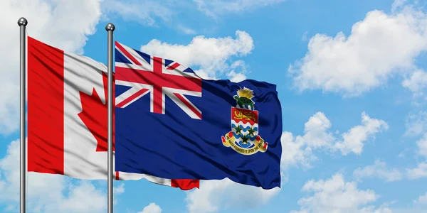 Bandera de Canadá y las Islas Caimán ondeando en el viento contra el cielo azul nublado blanco juntos. Concepto diplomático, relaciones internacionales . — Foto de Stock