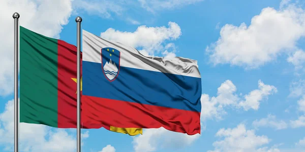 Cameroon and Slovenia flag waving in the wind against white cloudy blue sky together. Diplomacy concept, international relations.