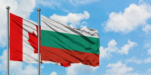 Bandera de Canadá y Bulgaria ondeando en el viento contra el cielo azul nublado blanco juntos. Concepto diplomático, relaciones internacionales . — Foto de Stock