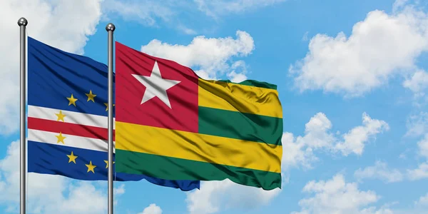 Bandera de Cabo Verde y Togo ondeando en el viento contra el cielo azul nublado blanco juntos. Concepto diplomático, relaciones internacionales . — Foto de Stock