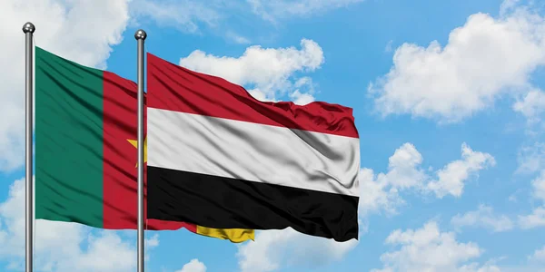 Bandera de Camerún y Yemen ondeando en el viento contra el cielo azul nublado blanco juntos. Concepto diplomático, relaciones internacionales . — Foto de Stock