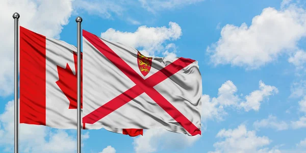 Bandera de Canadá y Jersey ondeando en el viento contra el cielo azul nublado blanco juntos. Concepto diplomático, relaciones internacionales . — Foto de Stock