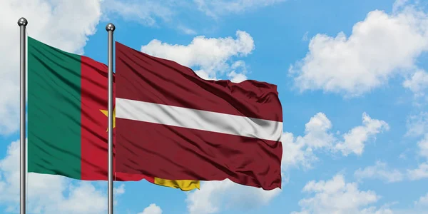 Camarões e Letônia acenando ao vento contra o céu azul nublado branco juntos. Conceito de diplomacia, relações internacionais . — Fotografia de Stock