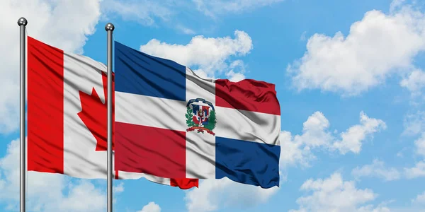 カナダとドミニカ共和国の旗は、一緒に白い曇り青い空に対して風に手を振る。外交概念、国際関係. — ストック写真