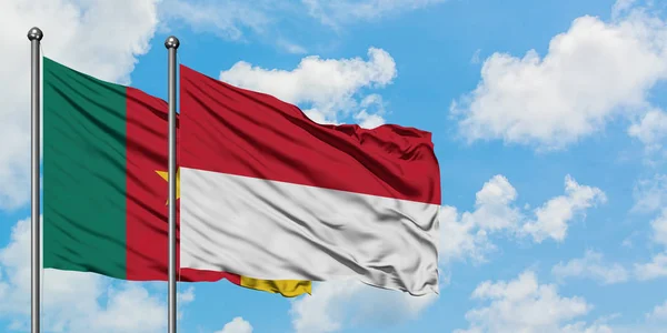 Bandera de Camerún e Indonesia ondeando en el viento contra el cielo azul nublado blanco juntos. Concepto diplomático, relaciones internacionales . — Foto de Stock
