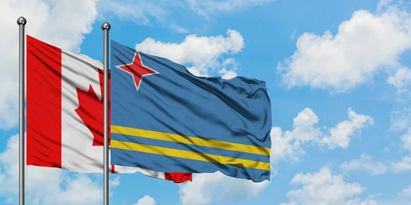 Bandera de Canadá y Aruba ondeando en el viento contra el cielo azul nublado blanco juntos. Concepto diplomático, relaciones internacionales . — Foto de Stock