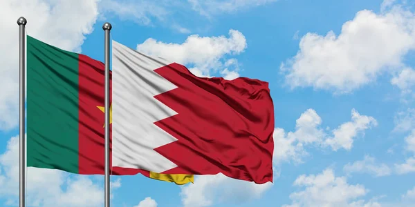 Bandera de Camerún y Bahréin ondeando en el viento contra el cielo azul nublado blanco juntos. Concepto diplomático, relaciones internacionales . — Foto de Stock