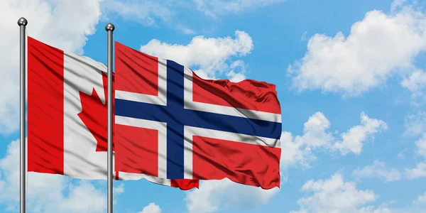 Bandera de Canadá y Bouvet Islands ondeando en el viento contra el cielo azul nublado blanco juntos. Concepto diplomático, relaciones internacionales . — Foto de Stock