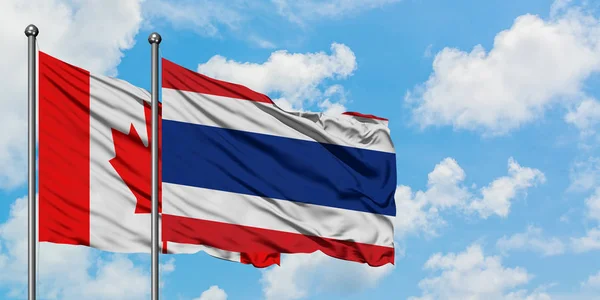 Bandeira do Canadá e Tailândia agitando no vento contra o céu azul nublado branco juntos. Conceito de diplomacia, relações internacionais . — Fotografia de Stock
