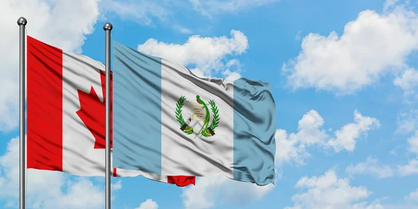 Kanada och Guatemala flagga vinka i vinden mot vit grumlig blå himmel tillsammans. Diplomatisk koncept, internationella relationer. — Stockfoto