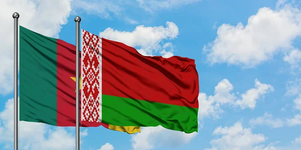Bandera de Camerún y Bielorrusia ondeando en el viento contra el cielo azul nublado blanco juntos. Concepto diplomático, relaciones internacionales . — Foto de Stock