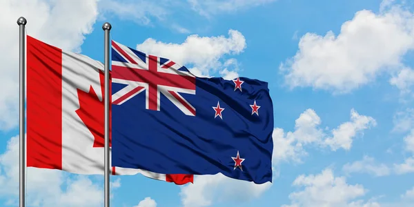 Bandera de Canadá y Nueva Zelanda ondeando en el viento contra el cielo azul nublado blanco juntos. Concepto diplomático, relaciones internacionales . —  Fotos de Stock