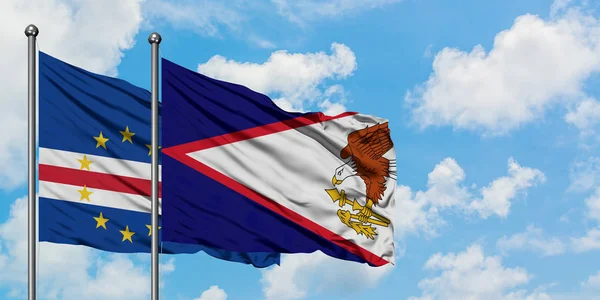 Bandera de Cabo Verde y Samoa Americana ondeando en el viento contra el cielo azul nublado blanco juntos. Concepto diplomático, relaciones internacionales . — Foto de Stock