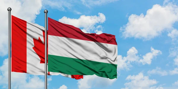 Canada and Hungary flag waving in the wind against white cloudy blue sky together. Diplomacy concept, international relations.