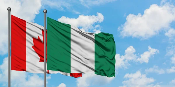 Bandera de Canadá y Nigeria ondeando en el viento contra el cielo azul nublado blanco juntos. Concepto diplomático, relaciones internacionales . — Foto de Stock
