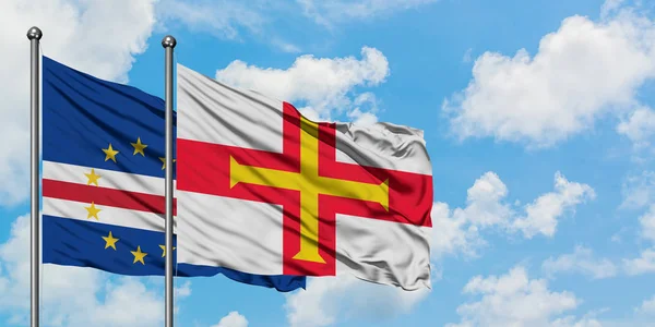 Bandera de Cabo Verde y Guernsey ondeando en el viento contra el cielo azul nublado blanco juntos. Concepto diplomático, relaciones internacionales . — Foto de Stock