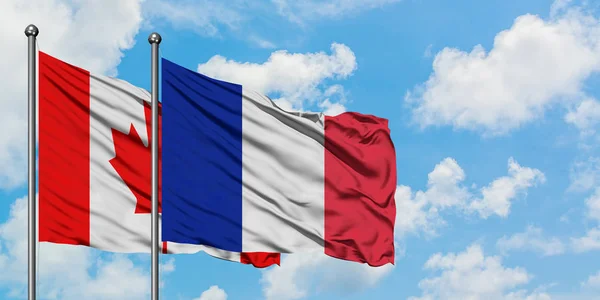 Bandera de Canadá y Reunión ondeando en el viento contra el cielo azul nublado blanco juntos. Concepto diplomático, relaciones internacionales . —  Fotos de Stock