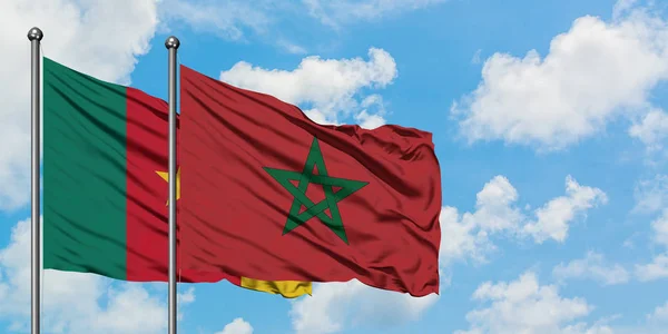 Bandera de Camerún y Marruecos ondeando en el viento contra el cielo azul nublado blanco juntos. Concepto diplomático, relaciones internacionales . — Foto de Stock