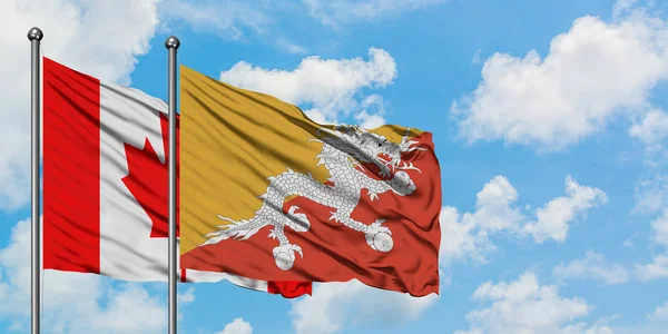 Bandera de Canadá y Bután ondeando en el viento contra el cielo azul nublado blanco juntos. Concepto diplomático, relaciones internacionales . — Foto de Stock