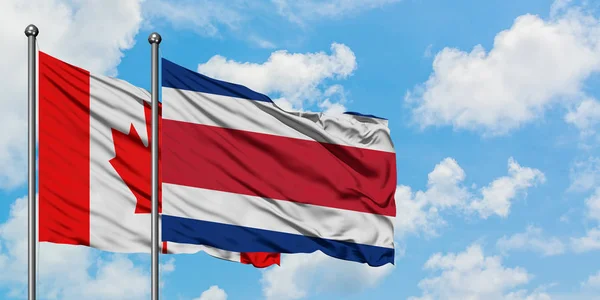 Canada e Costa Rica bandiera sventolando nel vento contro bianco cielo blu nuvoloso insieme. Concetto di diplomazia, relazioni internazionali . — Foto Stock