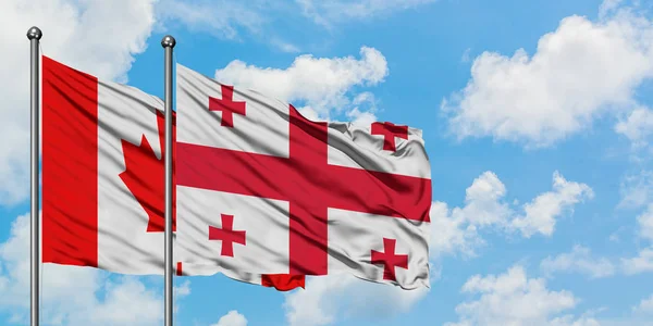 Bandera de Canadá y Georgia ondeando en el viento contra el cielo azul nublado blanco juntos. Concepto diplomático, relaciones internacionales . — Foto de Stock