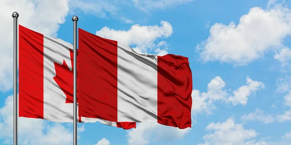 Η σημαία του Καναδά και του Περού κουνώντας τον άνεμο εναντίον του λευκού νεφελώδη μπλε ουρανού μαζί. Φιλοσοφία της διπλωματίας, διεθνείς σχέσεις. — Φωτογραφία Αρχείου