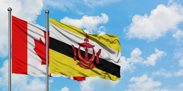 Bandera de Canadá y Brunei ondeando en el viento contra el cielo azul nublado blanco juntos. Concepto diplomático, relaciones internacionales . — Foto de Stock