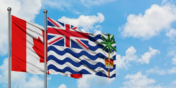 Bandera de Canadá y del Territorio Británico del Océano Índico ondeando en el viento contra el cielo azul nublado blanco juntos. Concepto diplomático, relaciones internacionales . — Foto de Stock