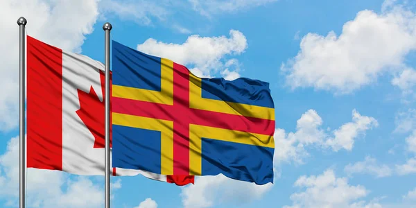 Kanada a Aland Islands vlajky se ve větru vlní proti bíle zatažené modré obloze. Diplomacie, mezinárodní vztahy. — Stock fotografie