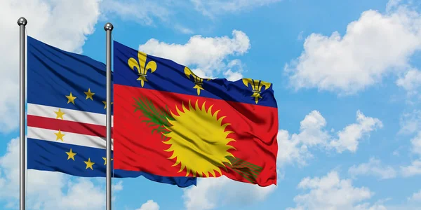 Bandera de Cabo Verde y Guadalupe ondeando en el viento contra el cielo azul nublado blanco juntos. Concepto diplomático, relaciones internacionales . — Foto de Stock